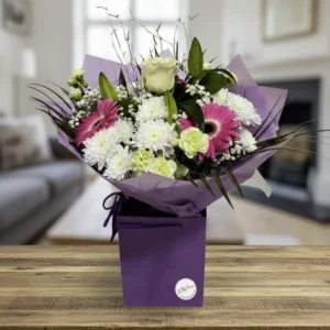 Blushing Snowfall winter bouquet with pink gerberas and white flowers in a purple gift box by Lili's Flowers Chester.