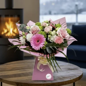 Elegant Splash bouquet with pink gerberas and roses in a pink gift box on a wooden table, hand-delivered by Lili's Flowers Chester