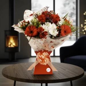 Fresh Aura Bouquet with red roses, red gerberas, and white chrysanthemums in a red gift box with a peach bow, delivered in Chester.